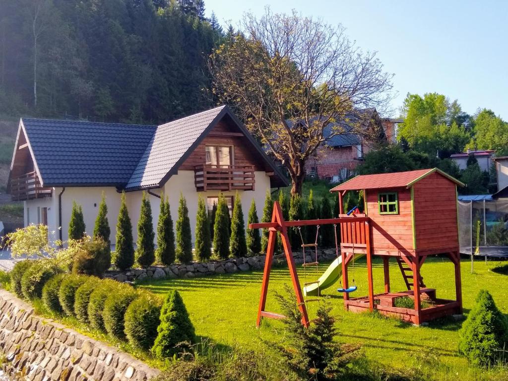 uma pequena casa com um parque infantil no quintal em Domek nad stawem em Krynica-Zdrój