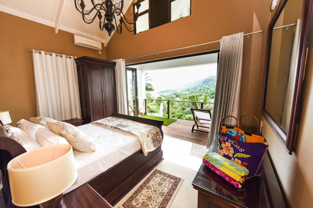 a bedroom with a bed with a view of a balcony at Coconut Climb in Mahe