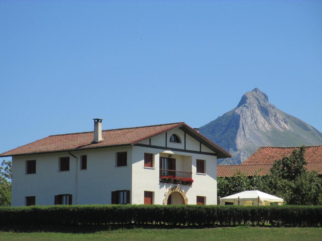 een wit huis met een berg op de achtergrond bij Lizargarate in Lazcano