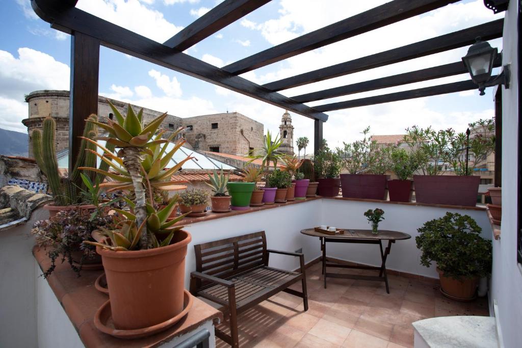 a balcony with potted plants and a table and chair at Rooms 19 B&B in Palermo