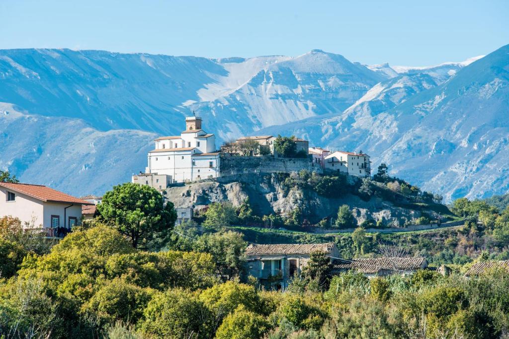 Palazzo Pulieri في Altino: ديره بيضاء على تل فيه جبال في الخلف