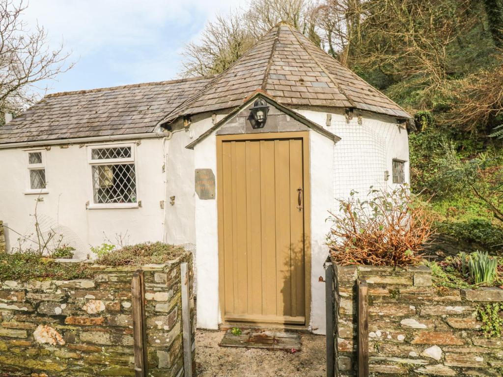 a small white house with a wooden door at Millstream in Tintagel