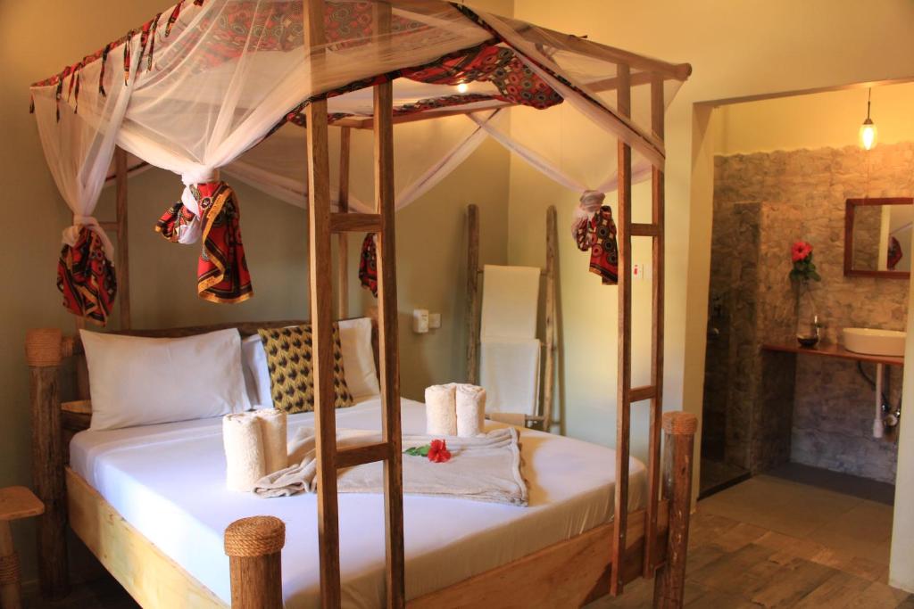 a bedroom with a canopy bed with white sheets at Chanya Lodge in Moshi