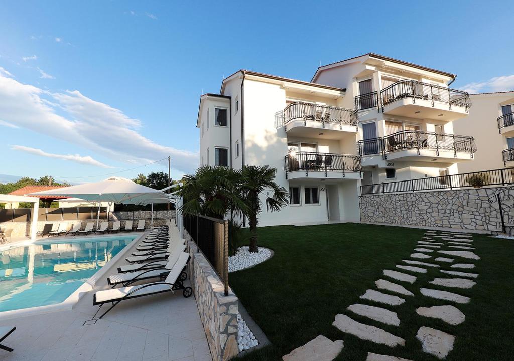 a building with a swimming pool next to a resort at Cool Šilo Appartement Resort in Šilo