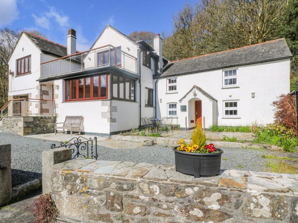 a large white house with a stone driveway at Carne Mill in Helston