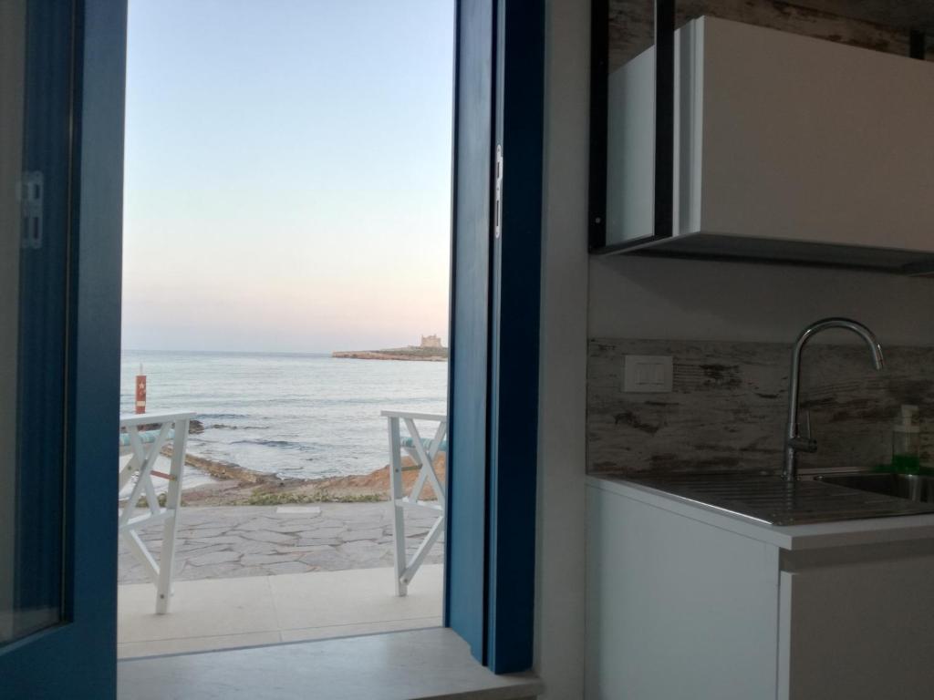 a kitchen with a view of the ocean through a door at La casetta di Portopalo in Portopalo