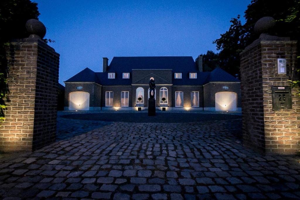 a large house with a brick driveway at night at VillaluX in Kortessem
