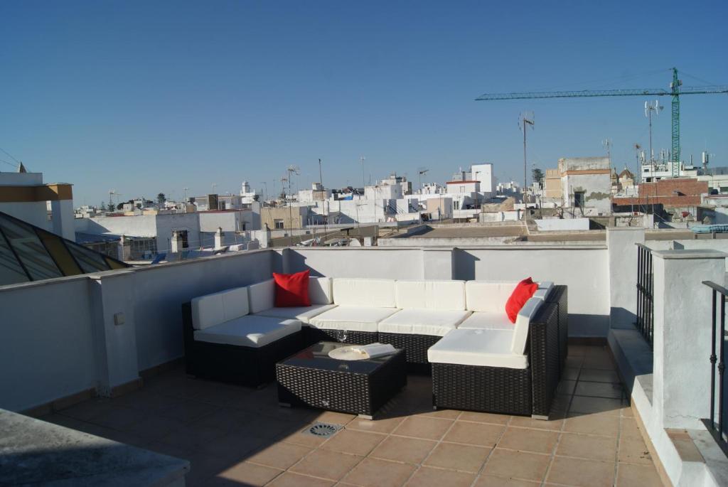 einen Balkon mit einem Sofa und Stühlen auf dem Dach in der Unterkunft CDZ - Ático Tavira two private terraces with great views in Cádiz