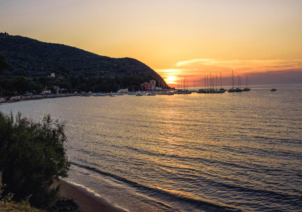 a sunset over a body of water with boats at Torre di Baratti Bio Resort in Populonia
