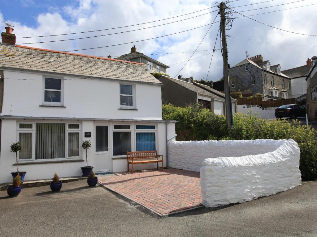 una casa blanca con un banco delante en The Keep Pot en Port Isaac