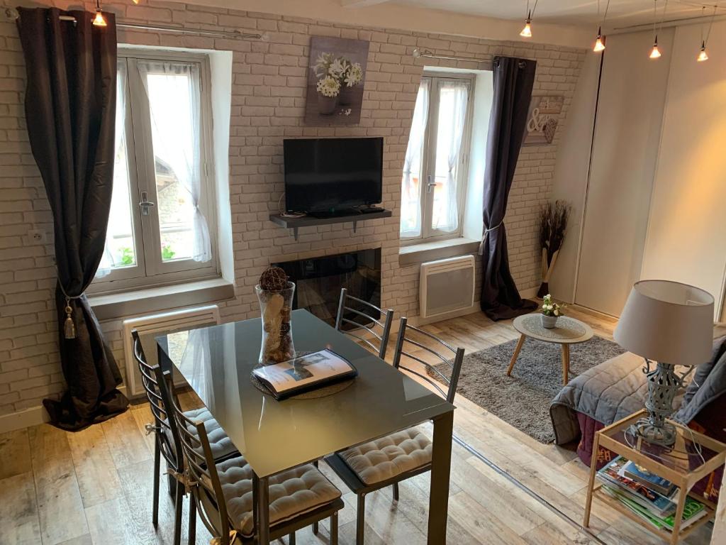 a living room with a table and a tv at Les Appartements Le Saint Pierre in Barcelonnette