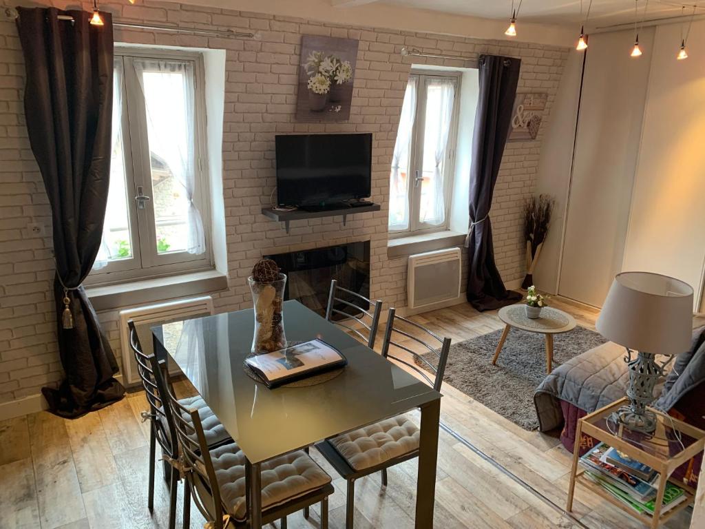 Una sala de estar con una mesa y un televisor. en Les Appartements Le Saint Pierre Barcelonnette, en Barcelonnette