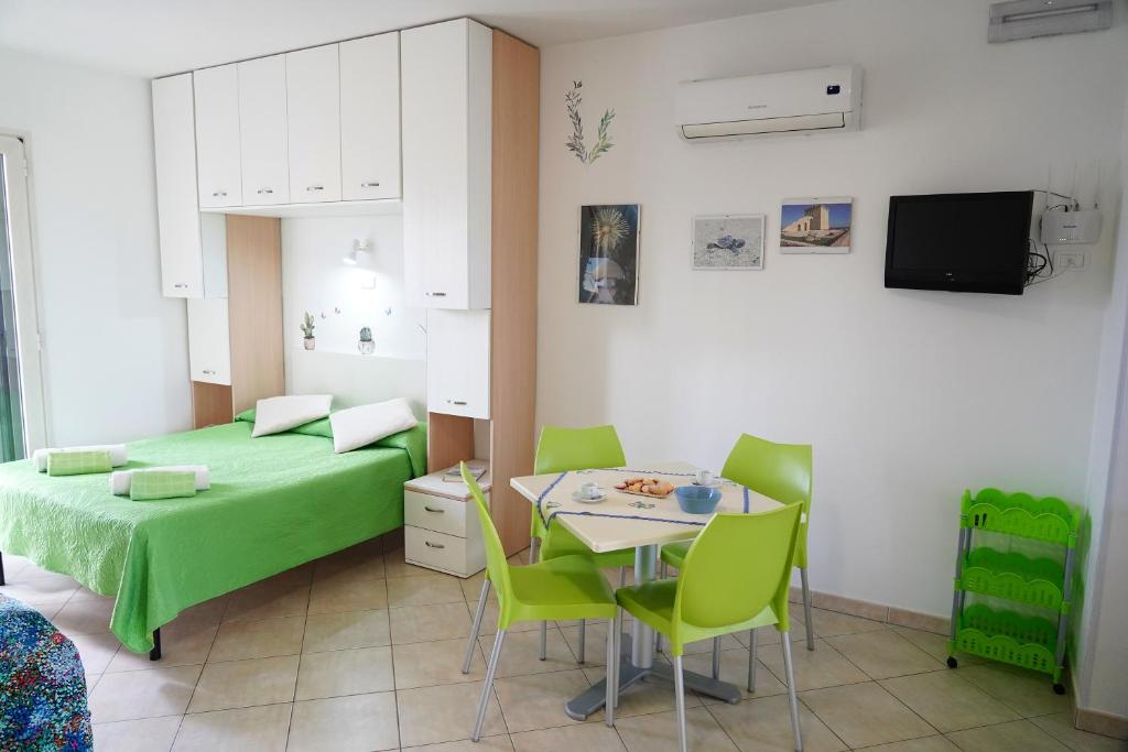 a bedroom with a green bed and a table and chairs at Dolly Monolocali in Porto Cesareo