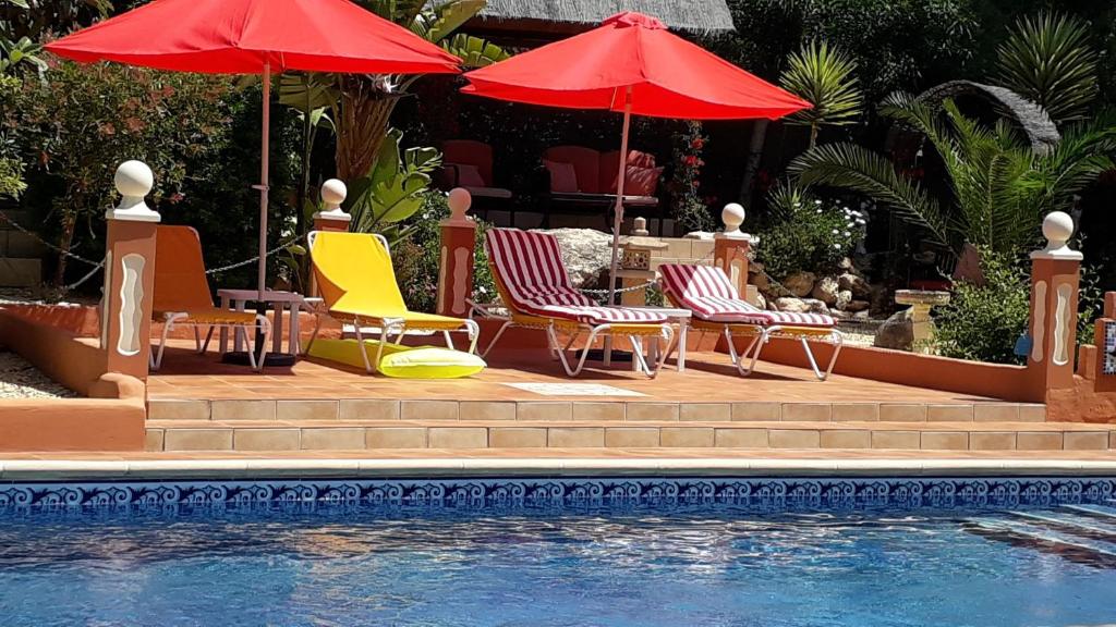 a group of chairs and umbrellas next to a pool at Villa Mimosa in Moraira