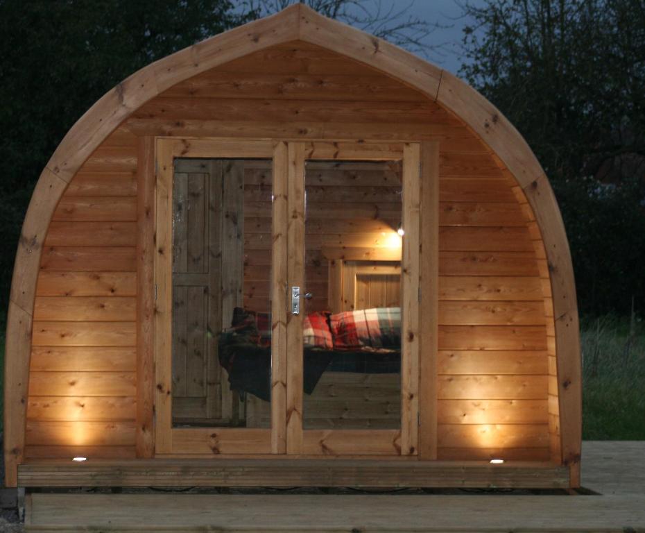 a large wooden dog house with an open door at Glamping at Spire View Meadow in Lincoln