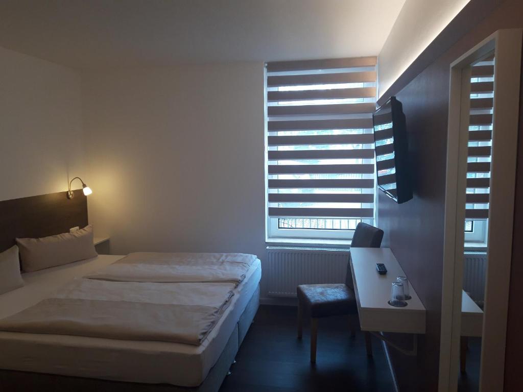 a bedroom with a bed and a desk and a window at Hotel Weinert in Neubrandenburg