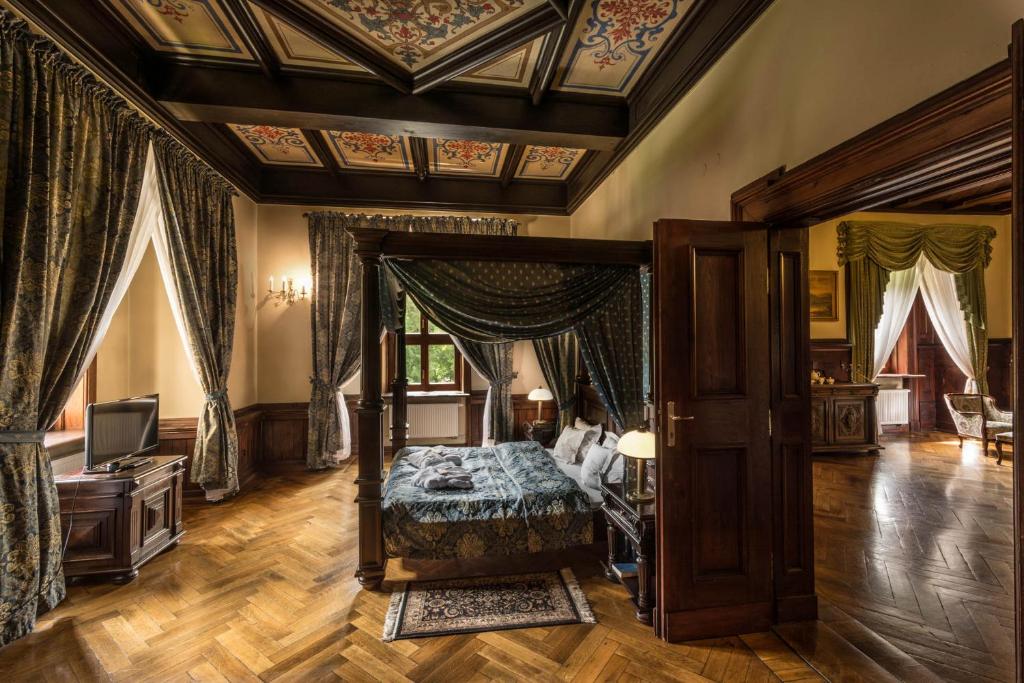 Luxurious bedroom with canopy bed, ornate ceiling, and connecting door to dining area.