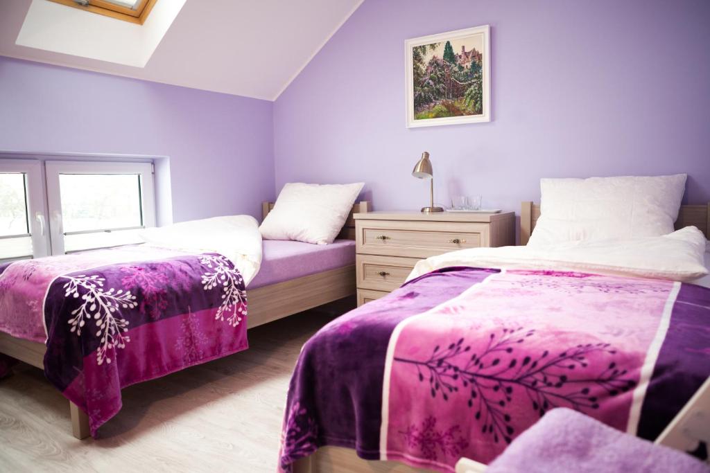 a purple bedroom with two beds and a dresser at "U Mamy Róży" - Pokoje Gościnne in Reda