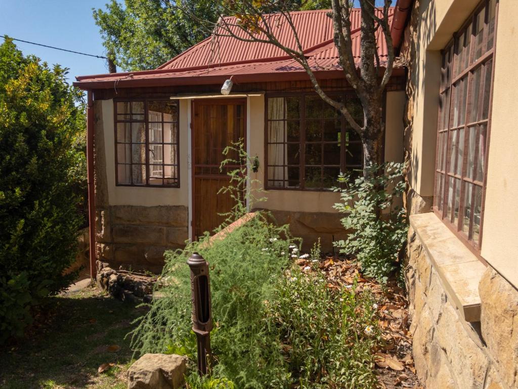 a small house with a red roof and a door at Berg Cottage in Clarens