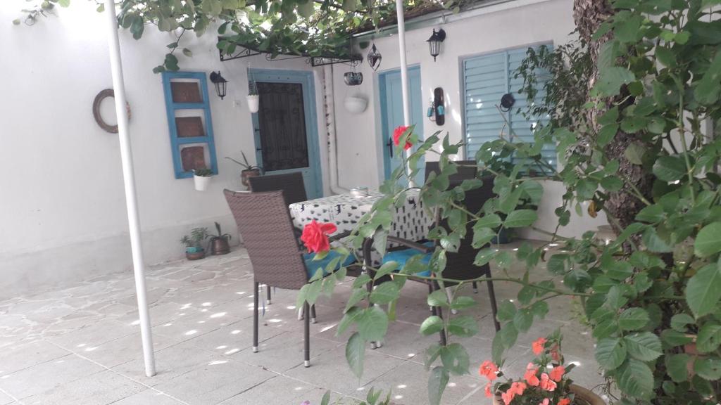 um pátio com 2 cadeiras e uma mesa com flores vermelhas em Apartment with garden Hanja em Mostar