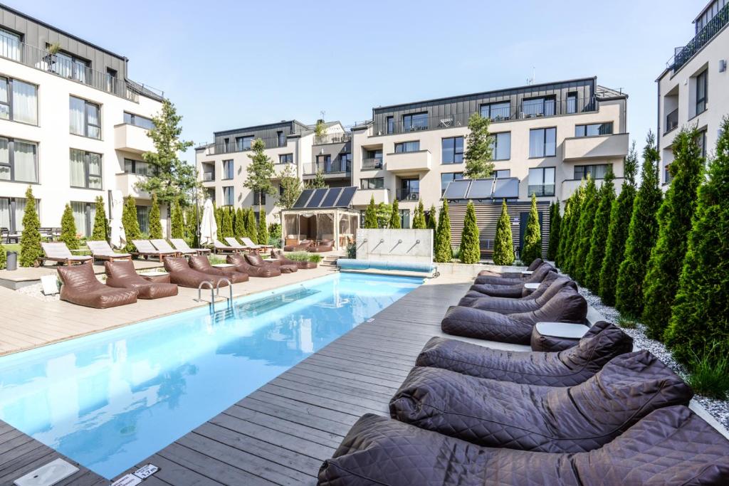 ein Swimmingpool mit Liegen und Stühlen neben Gebäuden in der Unterkunft Apartament Malūno in Palanga