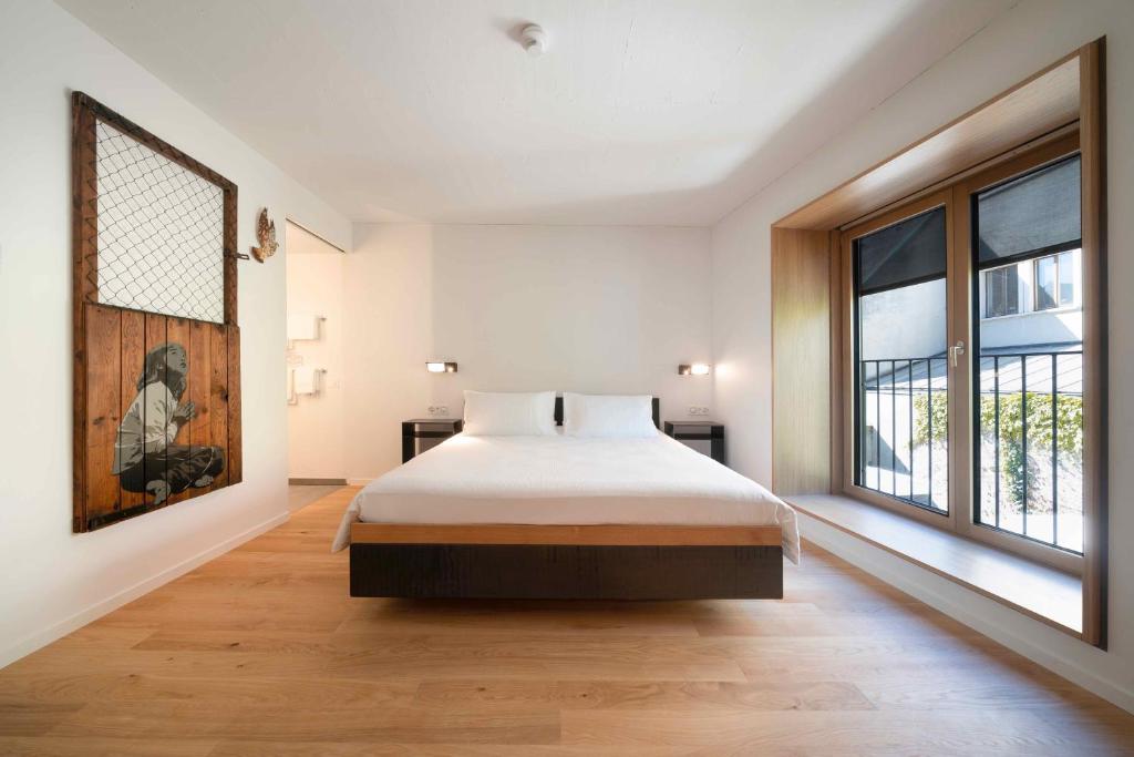 una camera da letto con un letto e una grande finestra di SET Hotel.Residence by Teufelhof Basel a Basilea