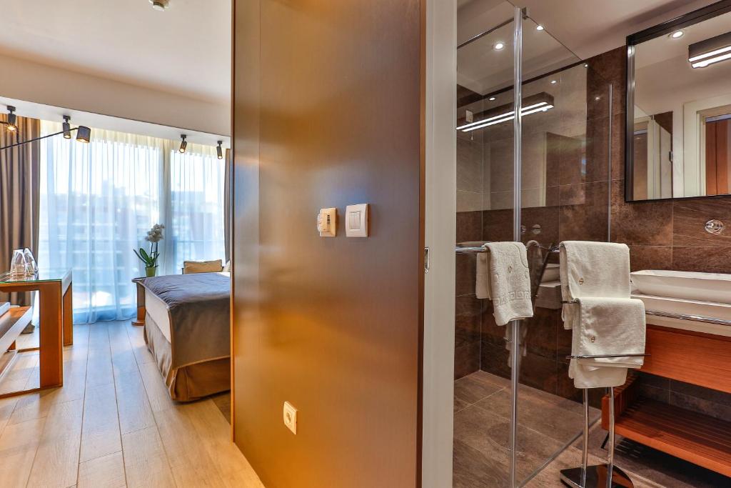 uma casa de banho com um chuveiro, um lavatório e uma cama em Hotel Fagus by Aycon em Budva