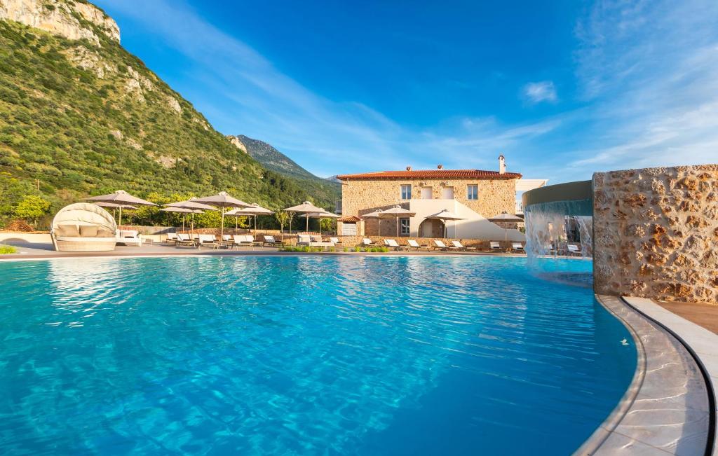 a pool at a resort with mountains in the background at Kyniska Palace Conference & Spa in Mystras