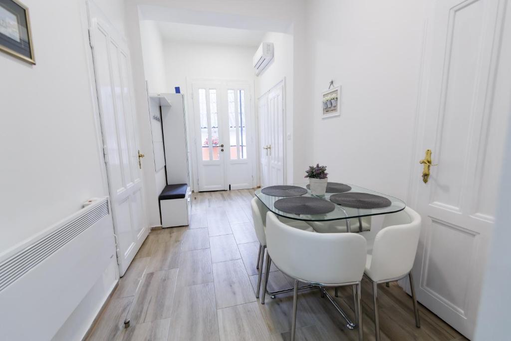 a dining room with a glass table and white chairs at Apartman Royal in Slavonski Brod