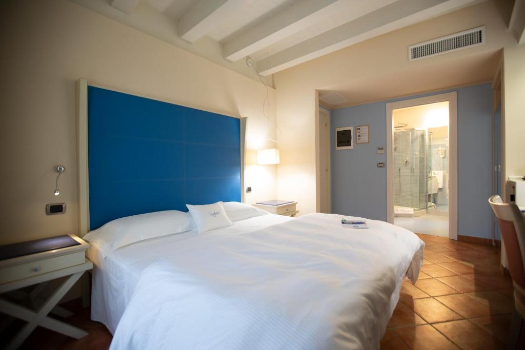 トロペアにあるポルテルコール B&Bのベッドルーム(青いヘッドボード付きの白い大型ベッド1台付)