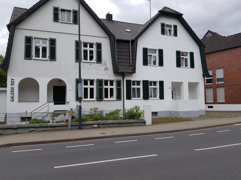 a white house with black windows and a street at Haus Roy in Zülpich