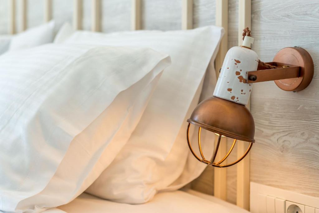 a light next to a bed with a pillow at Livikon by the Sea in Hora Sfakion