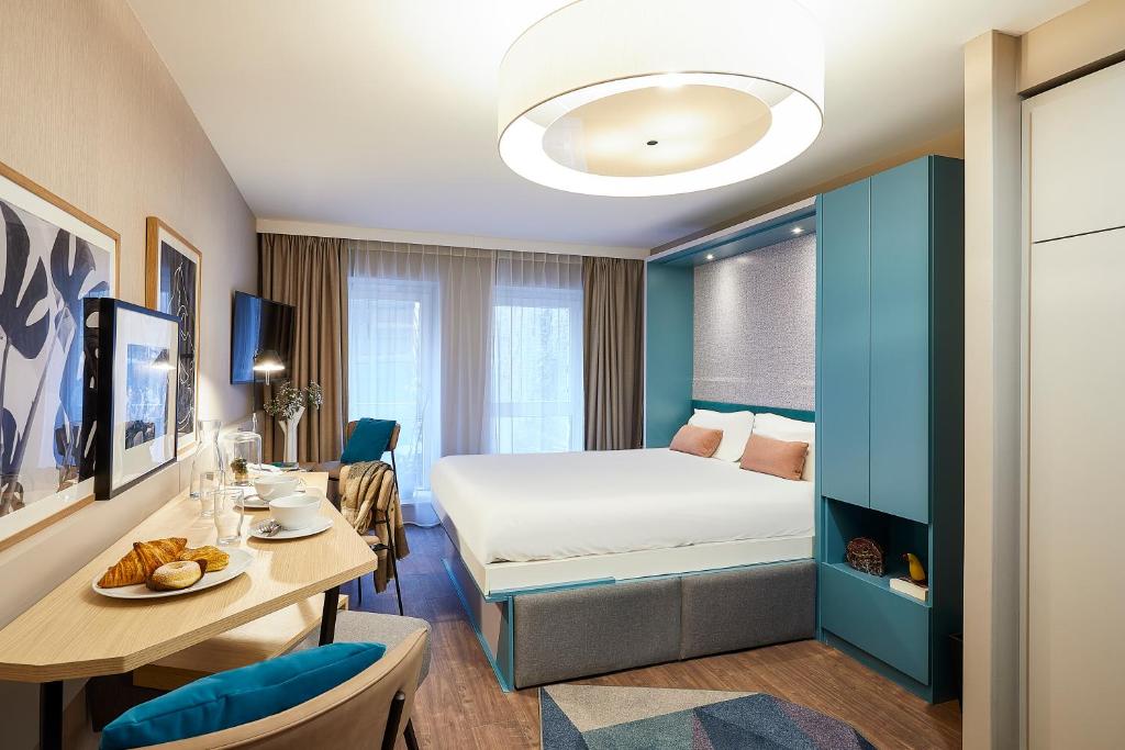 une chambre d'hôtel avec un lit, un bureau et une table dans l'établissement Aparthotel Adagio Lille Centre Grand Place, à Lille