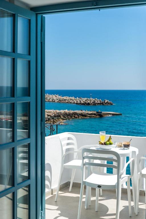 a table and chairs on a balcony with the ocean at Livikon by the Sea in Hora Sfakion