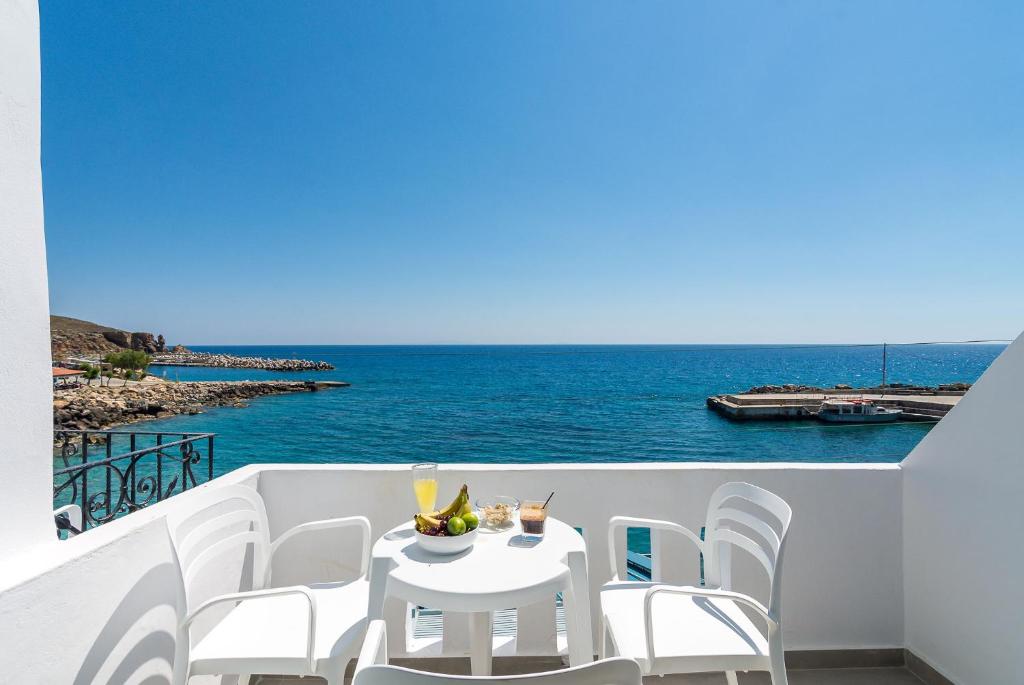 a white table and chairs on a balcony with the ocean at Livikon by the Sea in Hora Sfakion