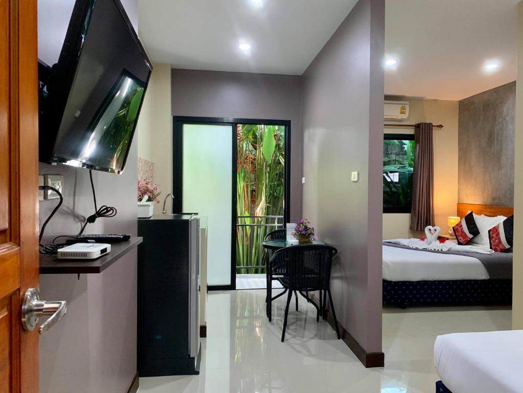 - une chambre avec un lit, une télévision et une table dans l'établissement Isayarada Apartment, à Thalang
