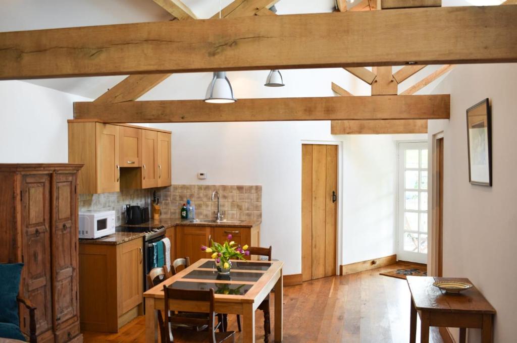 a kitchen with wooden beams and a table in a room at Burnhaies Farm Coach House in Cullompton