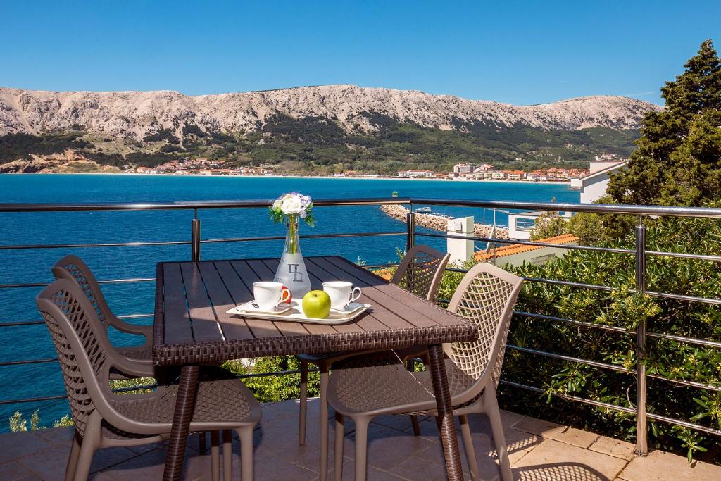 a table with a plate of fruit and a vase of flowers on it at Apartments Kricin II in Baška