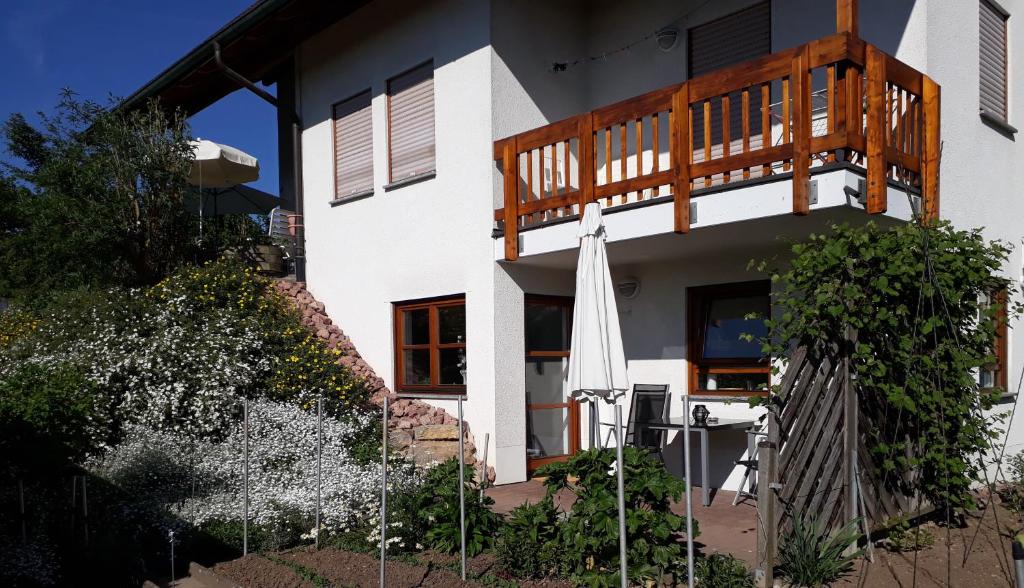 a white house with a balcony and an umbrella at 2-Zimmer-Ferienwohnung Gartenblick in Rottweil