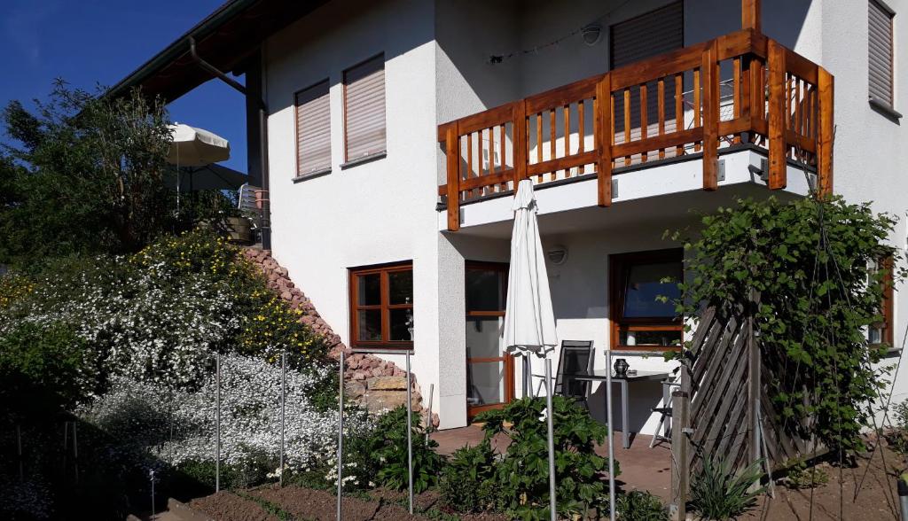 ein weißes Haus mit einem Balkon und einem Sonnenschirm in der Unterkunft 2-Zimmer-Ferienwohnung Gartenblick in Rottweil