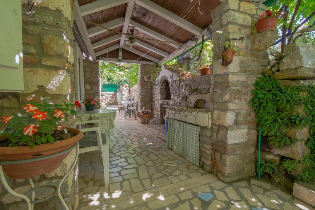 an outdoor kitchen with a stone wall and a patio at Loredana 1 in Veli Lošinj
