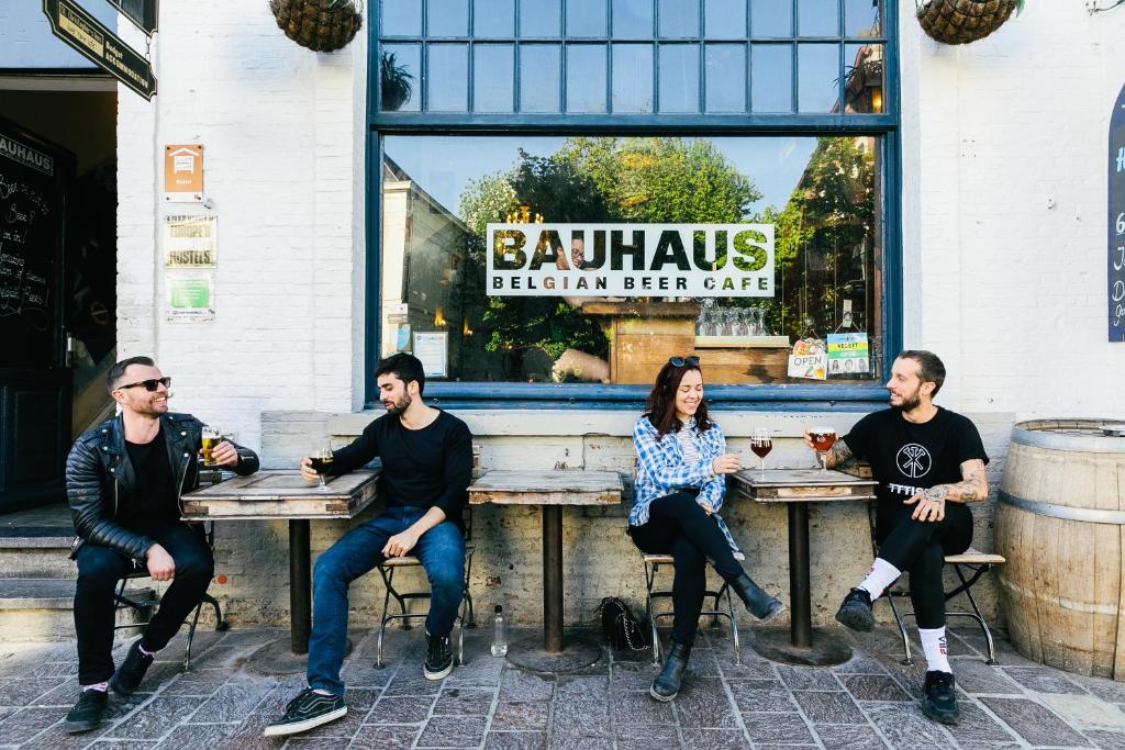 un grupo de personas sentadas en las mesas fuera de un restaurante en St Christopher's Inn Hostel at The Bauhaus en Bruges