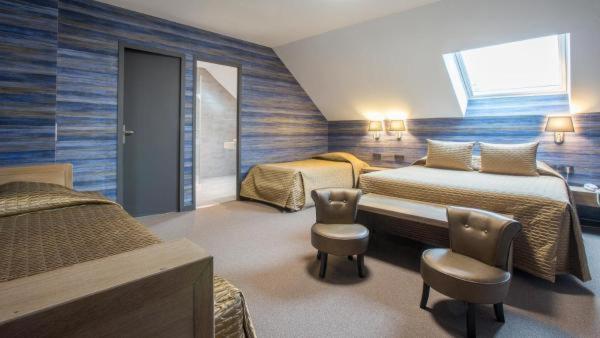 a hotel room with two beds and two chairs at Hostellerie St Vincent in Nuits-Saint-Georges