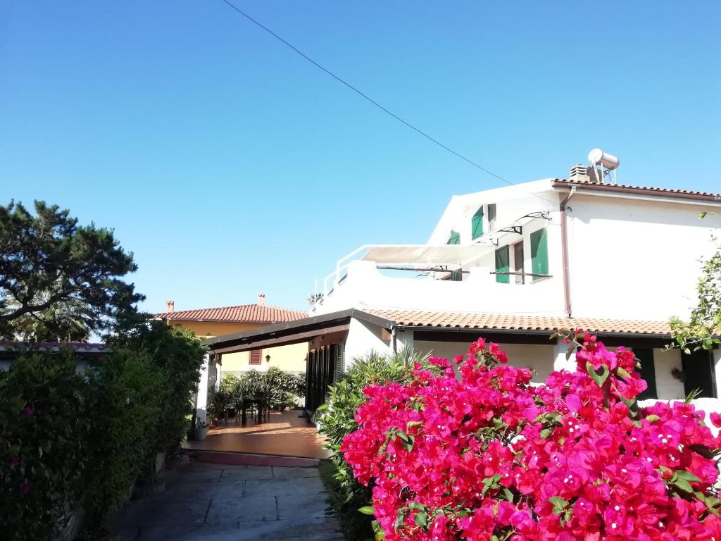 una casa con fiori rosa di fronte di Villa Maria Apartments a Capoterra