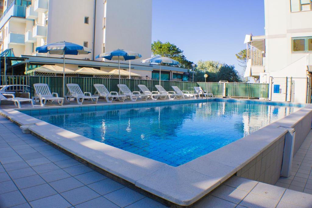 a swimming pool with chairs and umbrellas on a building at Hotel Brasilia in Lido di Classe