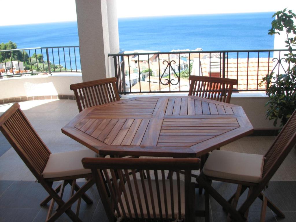 a wooden table and chairs on a balcony with the ocean at Apartments Leut in Sveti Stefan
