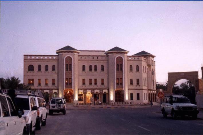 a large building with cars parked in front of it at Résidence El Arich in Tozeur