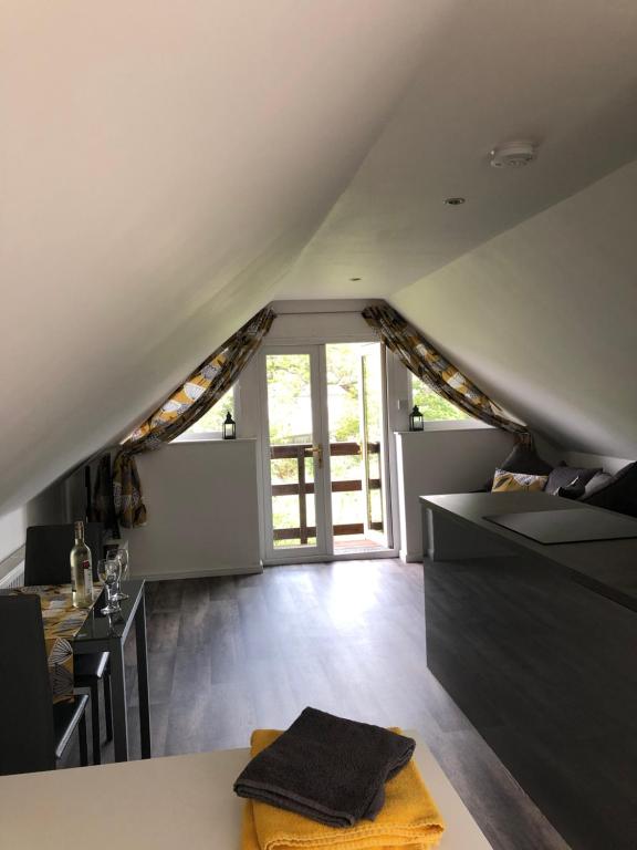 an attic room with a kitchen and a large window at The Tree House in Inverness