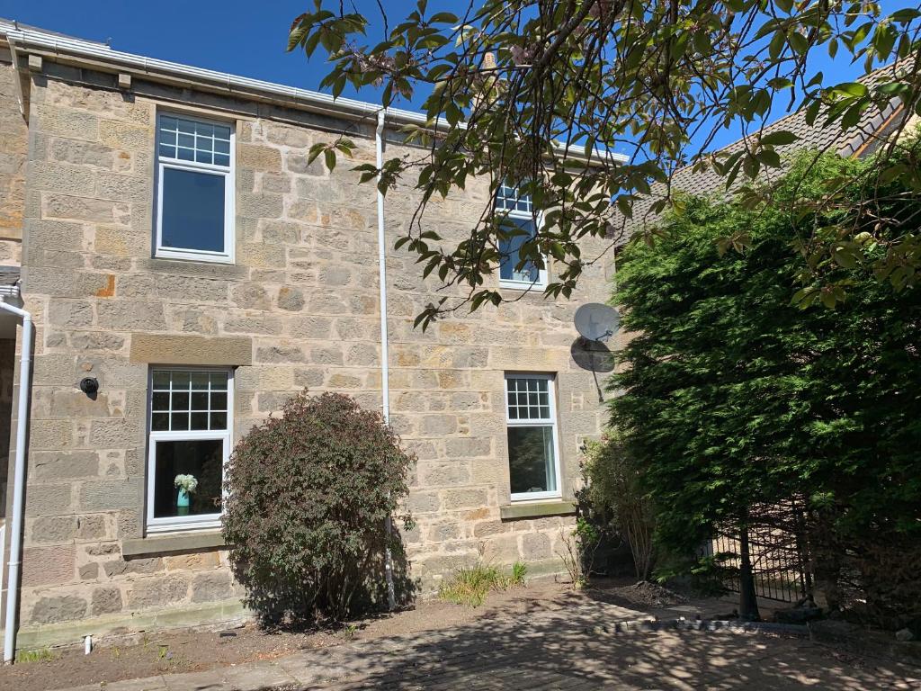 una casa de piedra con 2 ventanas y un arbusto en Cliffside en Lossiemouth