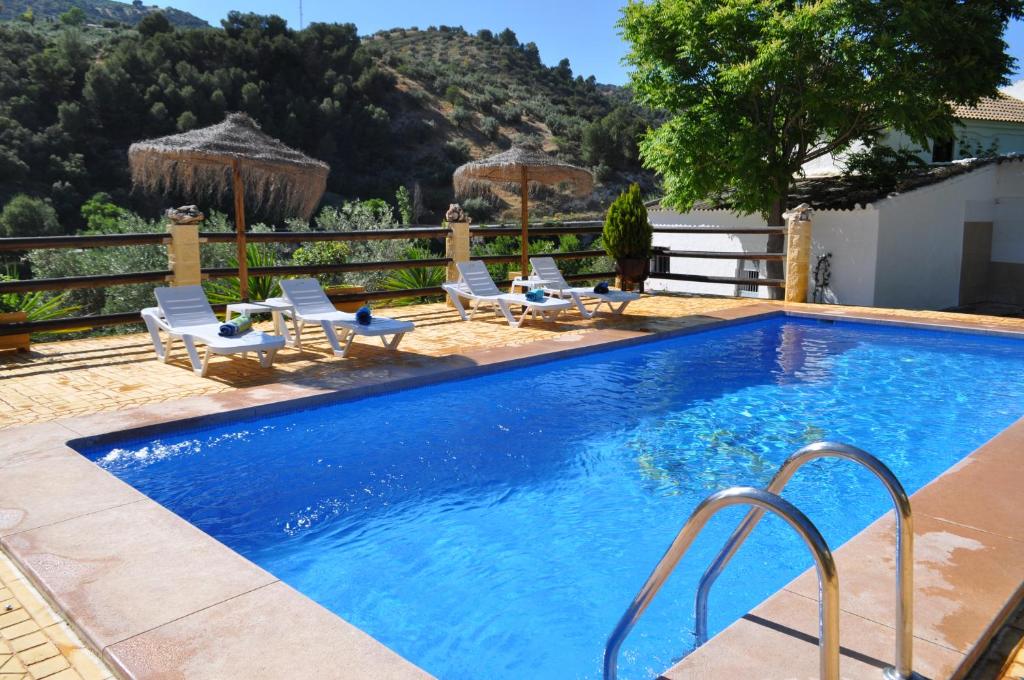 a swimming pool with lounge chairs next to a house at Cortijo Rural Las Nogueras in Cortijada Los Chorreros